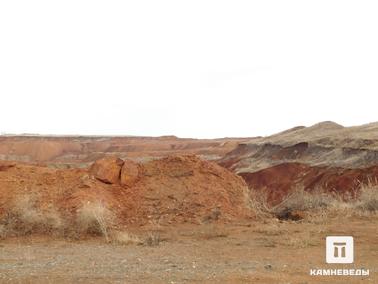 Вид на карьер Сахаринского месторождения. Отвалы месторождения богаты халцедонами, окрашенными в красноватый цвет, и окислами железа.