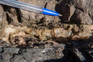 Кальцит. Кристаллический кальцит в прожилке между базальтом (вверху) и туфом (внизу).
Фото сделано на берегу Онежского озера, примерно 150-200 юго-западнее скал урочища Чертов Стул.